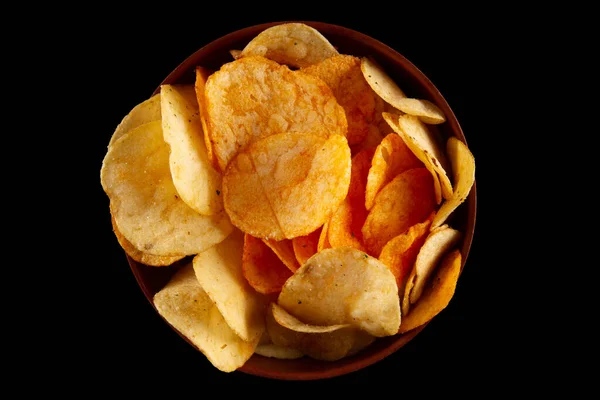 stock image Potato chips in clay bowl isolated on black background. Top view