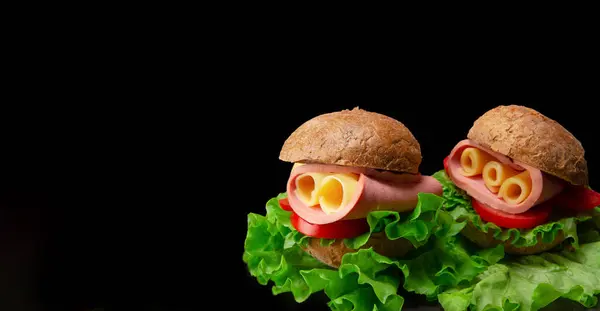 stock image Sandwich featuring lettuce, tomato, ham and cheese isolated on black background