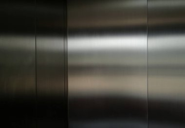 Stainless steel large sheet  With light hitting the surface  For background,Inside passenger elevator,Reflection of light on a shiny metal surface,stainless steel background.