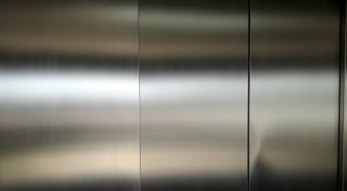 Stainless steel large sheet  With light hitting the surface  For background,Inside passenger elevator,Reflection of light on a shiny metal surface,stainless steel background.