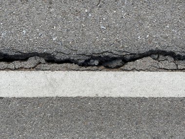 Asfalt yol dokusu ve çizgiler. Titreşimlerden dolayı yol yüzeyinde çatlaklar..