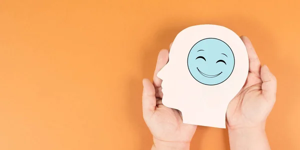 stock image Holding a head with a happy smiling face, mental health concept, positive mindset, support and evaluation symbol