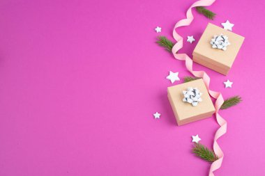 Küçük hediye kutularıyla, yıldızlarla ve köknar dallarıyla, pembe modaya uygun arka planla Noel tatili. 
