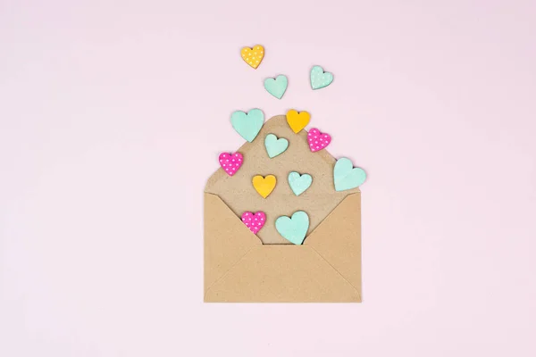 Valentine day greeting card, envelope with hearts on pastel background, love symbol, flat lay