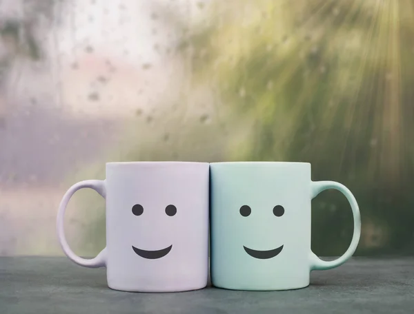 Happy, similing face, mug couple on a window sill cuddle, cup of coffee on a rainy day, support, relationship and friendship concept