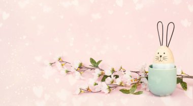 Tatlı Paskalya tavşanı ya da gülen yumurta suratlı tavşan. Bahar tatili tebrik kartı ve kiraz çiçekleri.