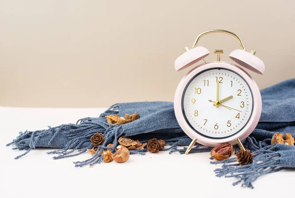 stock image Alarm clock with a scarf and nuts, end of daylight saving time in autumn, winter time changeover 