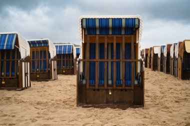 Baltık Sahili 'ndeki çatı hasır plaj sandalyeleri, Almanya' daki Kullanım Adası kıyıları, tuzlu su üzerinde fırtına ve yağmur, yüksek dalgalar, fırtına uyarısı