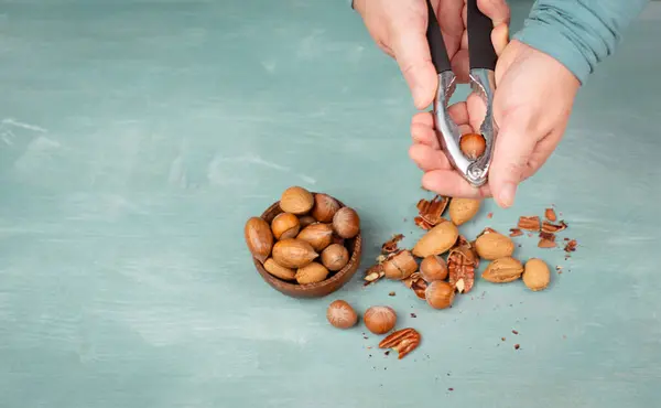 Crack nuts with a nutcracker, mix variety of almonds, hazelnuts and pecan nuts, healthy food and lifestyle