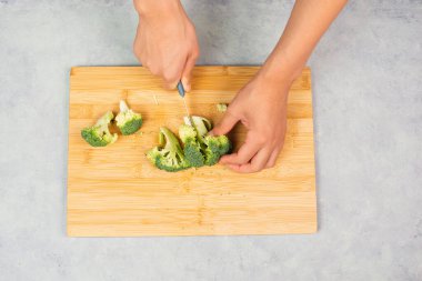 Tahtada brokoli kesmek, hazır olmak, sebzeli sağlıklı yemek, taze organik besin, yemek malzemeleri.