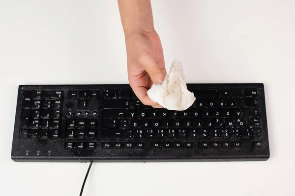 Cleaning computer keyboard in office with a wet wipe rag, dusty and dirty electronic, housework
