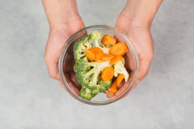 Elinde taze organik brokoli ve havuç tutarken, sebze, hasat ve tarım ile sağlıklı yiyecekler hazırla.