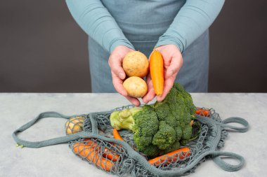 Sebzeli patates torbası, alışveriş bakkalı, sağlıklı gıda malzemeleri, brokoli ve havuç alan eller. 