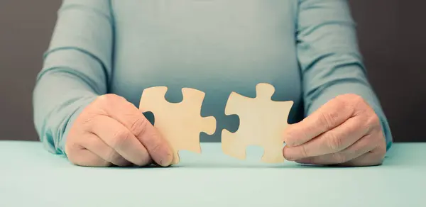 Holding two pieces of a puzzle in the hands, connecting together as a team, solving a problem, strategy and communication concept