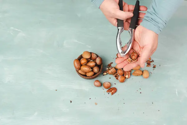 Crack nuts with a nutcracker, mix variety of almonds, hazelnuts and pecan nuts, healthy food and lifestyle
