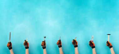 Elinde farklı aletler olan usta ya da tamirci, işçi günü, el işi ve çırak, çekiç, kerpeten ve çelenk.