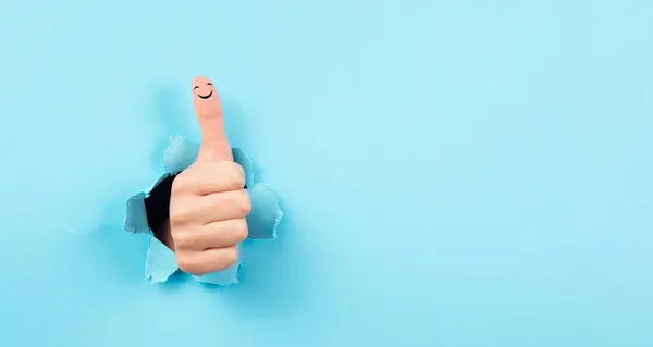 Baş parmak yukarı, gülen surat, olumlu el hareketi, onay ya da anlaşma, iyimserlik ve duygu, yırtık mavi kağıt.