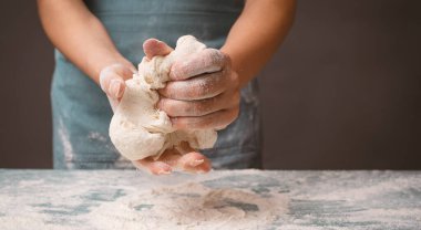 Elleriyle pizza ya da zanaatkar ekmeği yoğurmak için hamur yoğurur, yemek için malzeme hazırlar, pasta pişirir. 