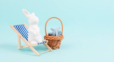 Bunny or rabbit sitting on lounge chair, basket with sea stars, easter holiday, vacation by the sea