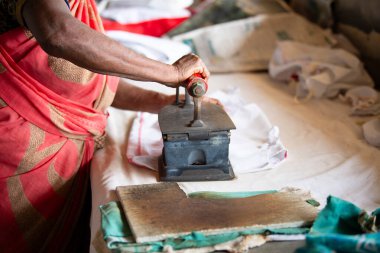 Geleneksel giysili kadın elinde antika bir kömür ütüsüyle, Dhobi Ghat, Kochi, Hindistan 'da hava çamaşırhanesi açıyor.