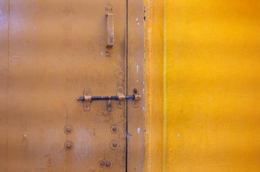 Eski yıpranmış kapı kilitli, parlak sarı eski püskü bir renk, Hindistan