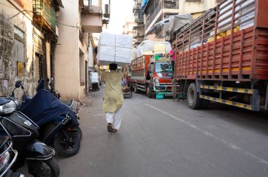 Mumbai sokakları, Mescid Bunder, Hindistan, küçük işletme ve gecekondu işçisi, kafasında bir paket taşıyan adam, 04.03.2025