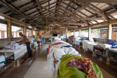Geleneksel Hint elektrikli ütüsüyle çalışan adam, Dhobi Ghat, Kochi, Hindistan 'da açık hava çamaşırları, eski ütü aletleri, 29.03.202