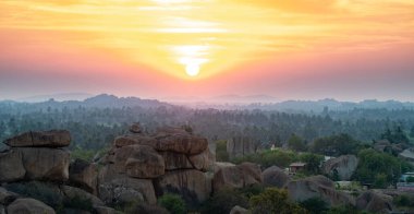Hindistan 'ın Hampi kentindeki Hemakuta Tepesi' nden gün batımı manzarası tropikal ağaçlarla kaplı kaya manzarası, Güney Hindistan, Karnataka, seyahat merkezi.
