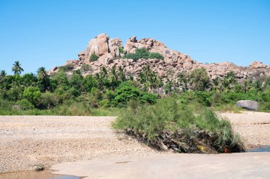 Tungabhadra nehrinde çalıları ve ağaçları olan Hampi kayaları, kayalık arazi, Güney Hindistan, Karnataka