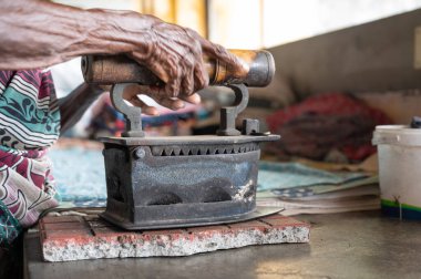 Geleneksel giysili kadın elinde antika bir kömür ütüsüyle, Dhobi Ghat, Kochi, Hindistan 'da hava çamaşırhanesi açıyor.