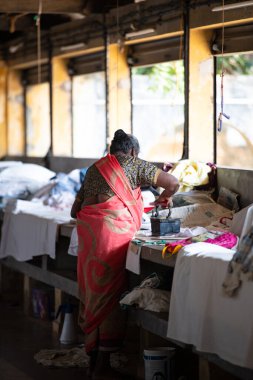 Geleneksel giysili kadın antika bir kömür ütüsüyle, Dhobi Ghat, Kochi, Hindistan 'da hava çamaşırları, 29.03.2025