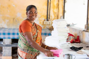 Geleneksel kıyafet katlayan kadın, Dhobi Ghat, Kochi, Hindistan 'da hava çamaşırları, 20 Mart 2025