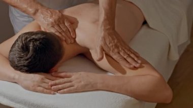 Kaslı erkeklere yakın omuzlar masajı. Erkek eller SPA salonunda ya da klinikte profesyonel masaj yapıyor. Vücut ve sağlık hizmetleri kavramı, alternatif tıp.