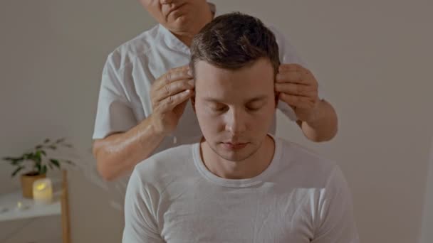 Młody Mężczyzna Relaksuje Się Podczas Profesjonalnego Masażu Głowy Salonie Spa — Wideo stockowe