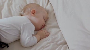 Yatağında huzur içinde yatan uyuyan bir bebeğin huzurlu bir yakın çekimi. Çocukluğun sevimli ve iç açıcı anı.. 