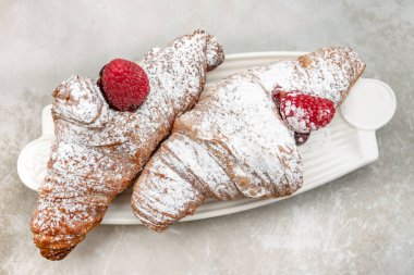 Croissants with jam and berries for Breakfast. Behind, a defocus background.