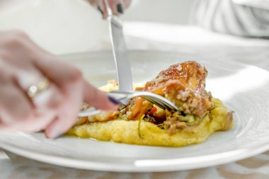 Beyaz bir porselen tabakta servis edilen mikro yeşillikli İtalyan polentasıyla pişirilmiş rosto. İtalyan yemeği..