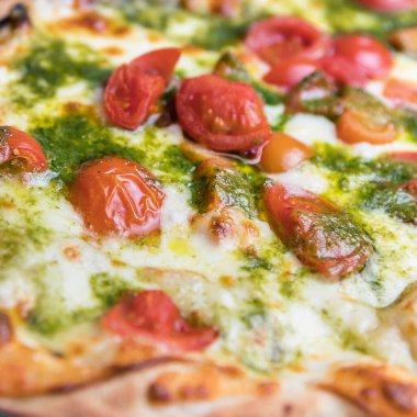 Kapalı pizza. Kiraz domatesli İtalyan pizzası, fesleğen sosu ve ahşap fırında pişirilmiş mozzarella peyniri. İtalyan mutfağı.