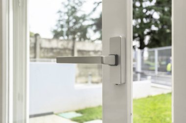 Alüminyum pencere açık. Metal kapı çerçeve yakın çekim görüntüsü. Ses yalıtımı. Enerji tasarrufu, güvenlik profili, bulanık bahçe arka planı.