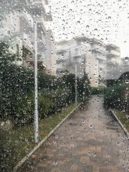 Pencereye yağmur damlaları düşer. Yağmurlu ve yağmurlu bir günde pencereden dışarı bakıyorum..