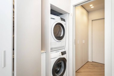 Çamaşır makinesi ve çamaşır kurutma makinesi olan modern çamaşır odasının içinde.