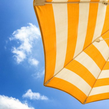 Mavi gökyüzüne karşı beyaz ve turuncu şemsiye. Tatil zamanı..