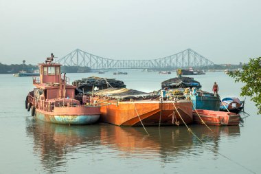 Tekneler Kolkata 'daki Ganj nehrine yanaştı. Arka planda Howrah Köprüsü, Batı Bengal 'deki Hooghly Nehri üzerinde görünen dengeli bir kantilever köprüdür..