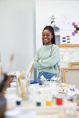 Young woman is in her painting studio. She is posing for the portrait photo of her working there