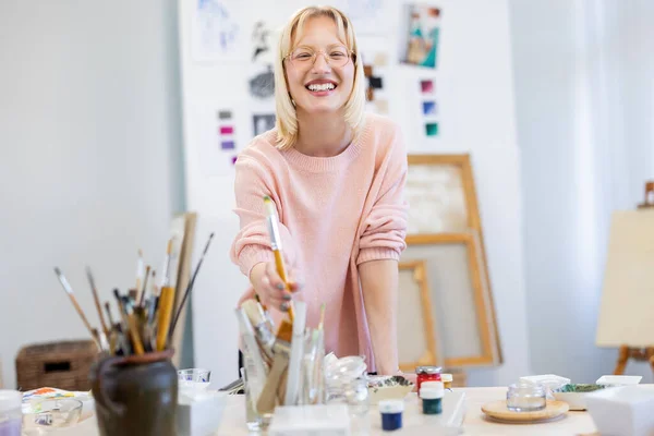 Jonge Vrouw Haar Schilderatelier Lacht Camera Voor Haar Werktafel — Stockfoto