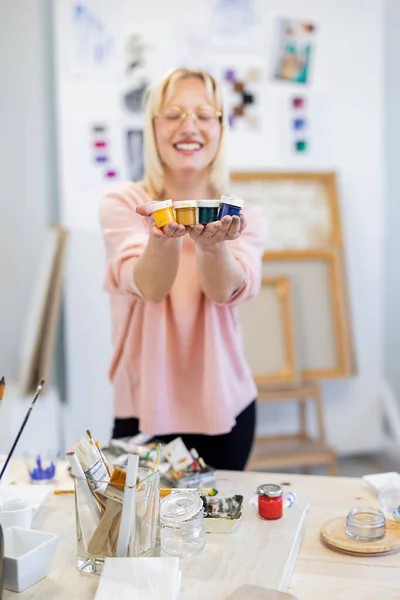 年轻的画家在工作室里拿着装有油漆的瓶子 她站在工作台前 — 图库照片