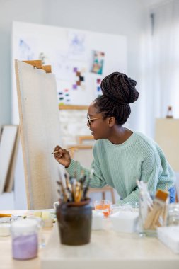 Atölyesinde çalışan genç ressam, yeni tuvale resim yapmaya başlıyor.