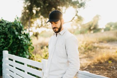 Kırsalda siyah şapkalı genç bir sakallı adamın portresi.