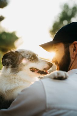 Kırsalda, siyah şapkalı, köpeğiyle birlikte sakallı bir adamın portresi.