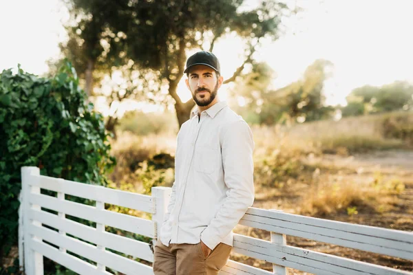 stock image Portrait of a young bearded man wearing a black cap at countryside